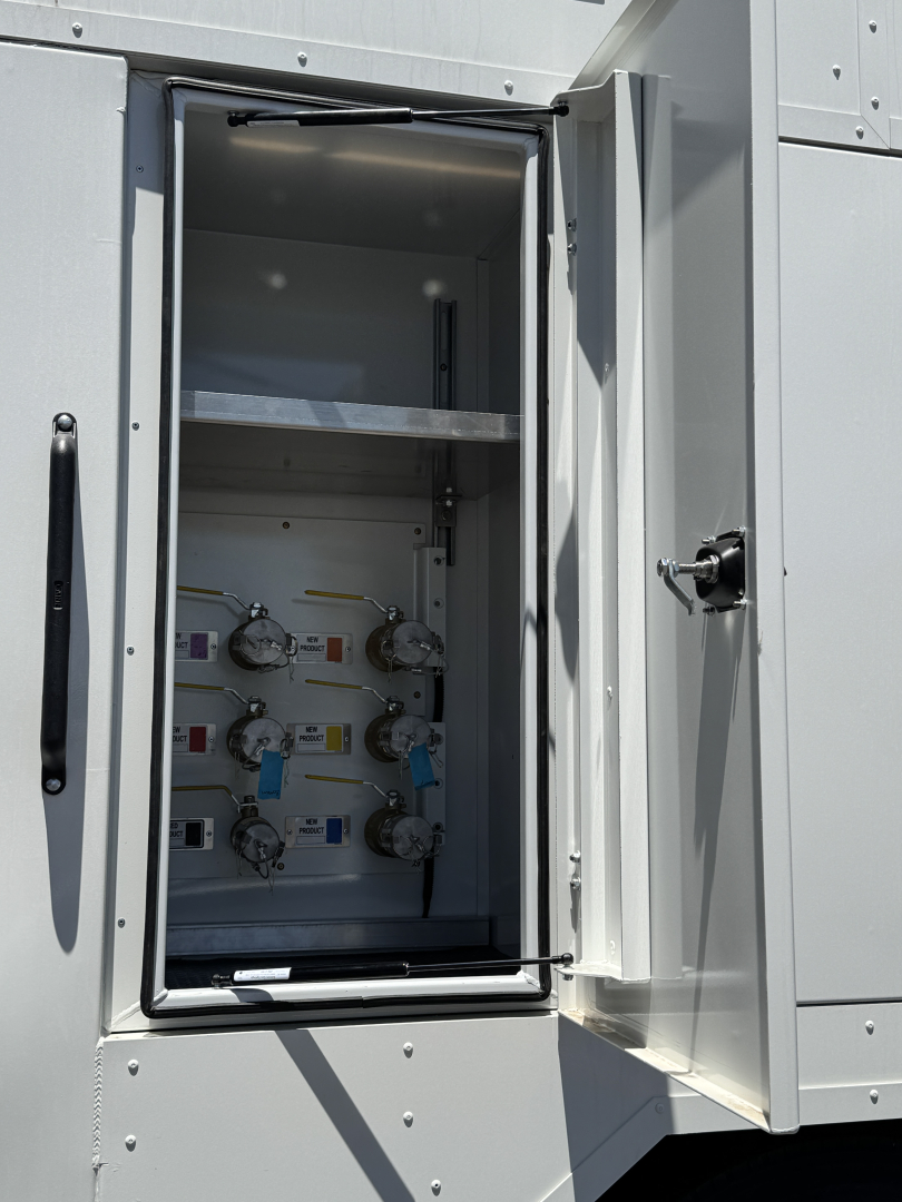 Mack MD7 service truck equipment cabinet with multiple valves and gauges inside a recessed compartment