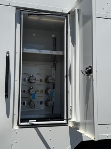 Mack MD7 service truck equipment cabinet with multiple valves and gauges inside a recessed compartment