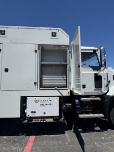 Mack MD7 service utility truck side showing exterior storage compartments, open rear compartment with shelves, and a Vanair system box labeled Vanair Reliant AC-04.