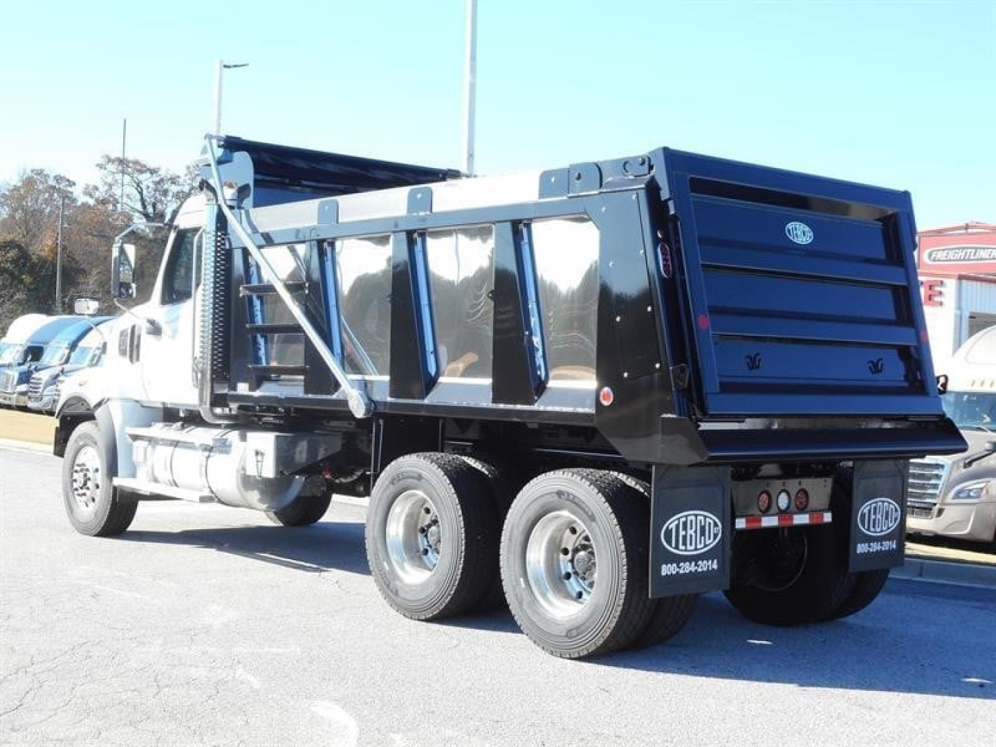 Dump truck in-service showing Western Star 47X dump bed with three rear axles and dual rear tires.