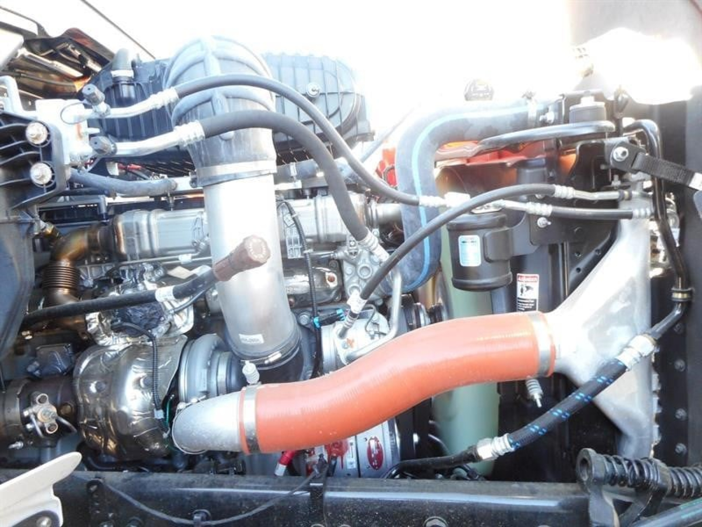 Western Star 47X engine bay showing large orange coolant hose and various hoses, metal components, and a cylindrical filter.