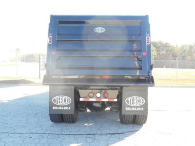 Rear view of a blue Western Star dump truck bed on a truck chassis, with TEBCO branding on mud flaps and tailgate, showing the dual rear wheels and bumper area.