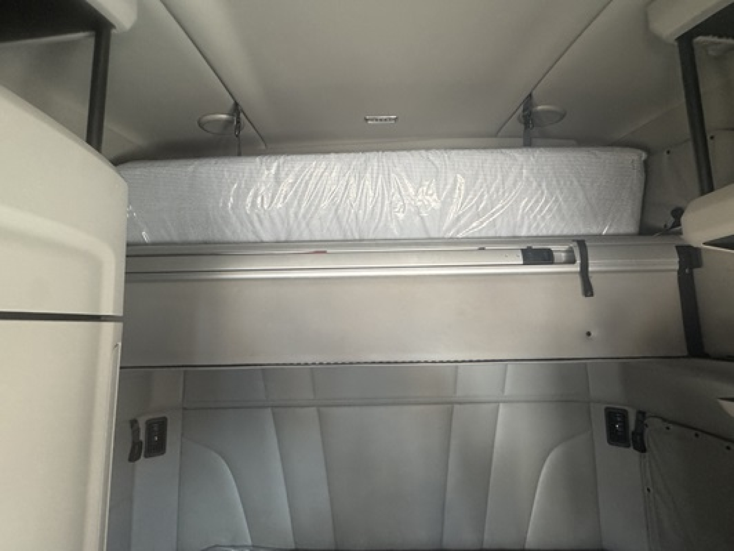 Trucks cab interior showing sleeper berth with mattress and storage shelves in a Peterbilt 579 cabin.