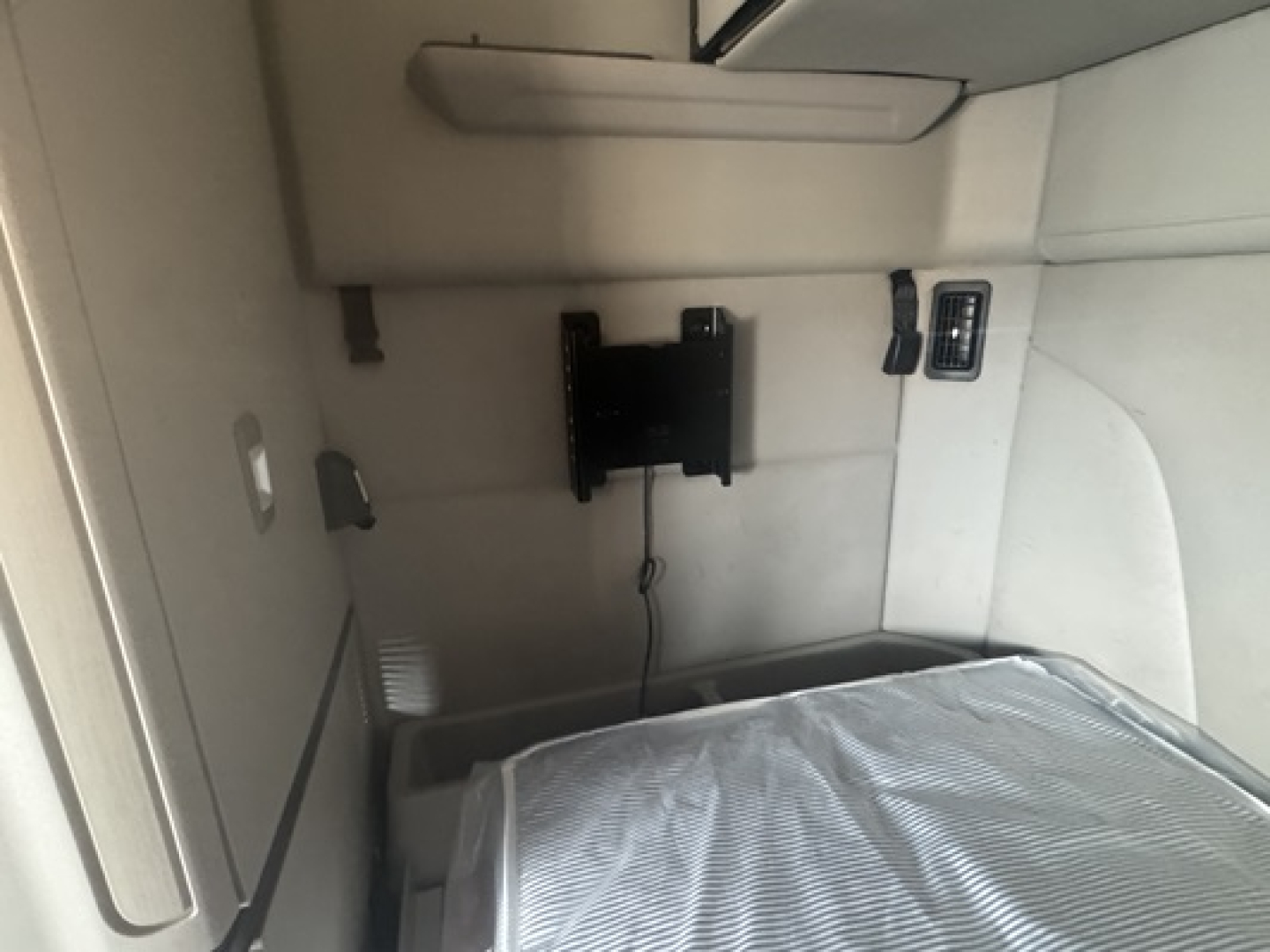 Peterbilt 579 cab interior showing sleeper area with mounting bracket and power outlet, view from passenger side.