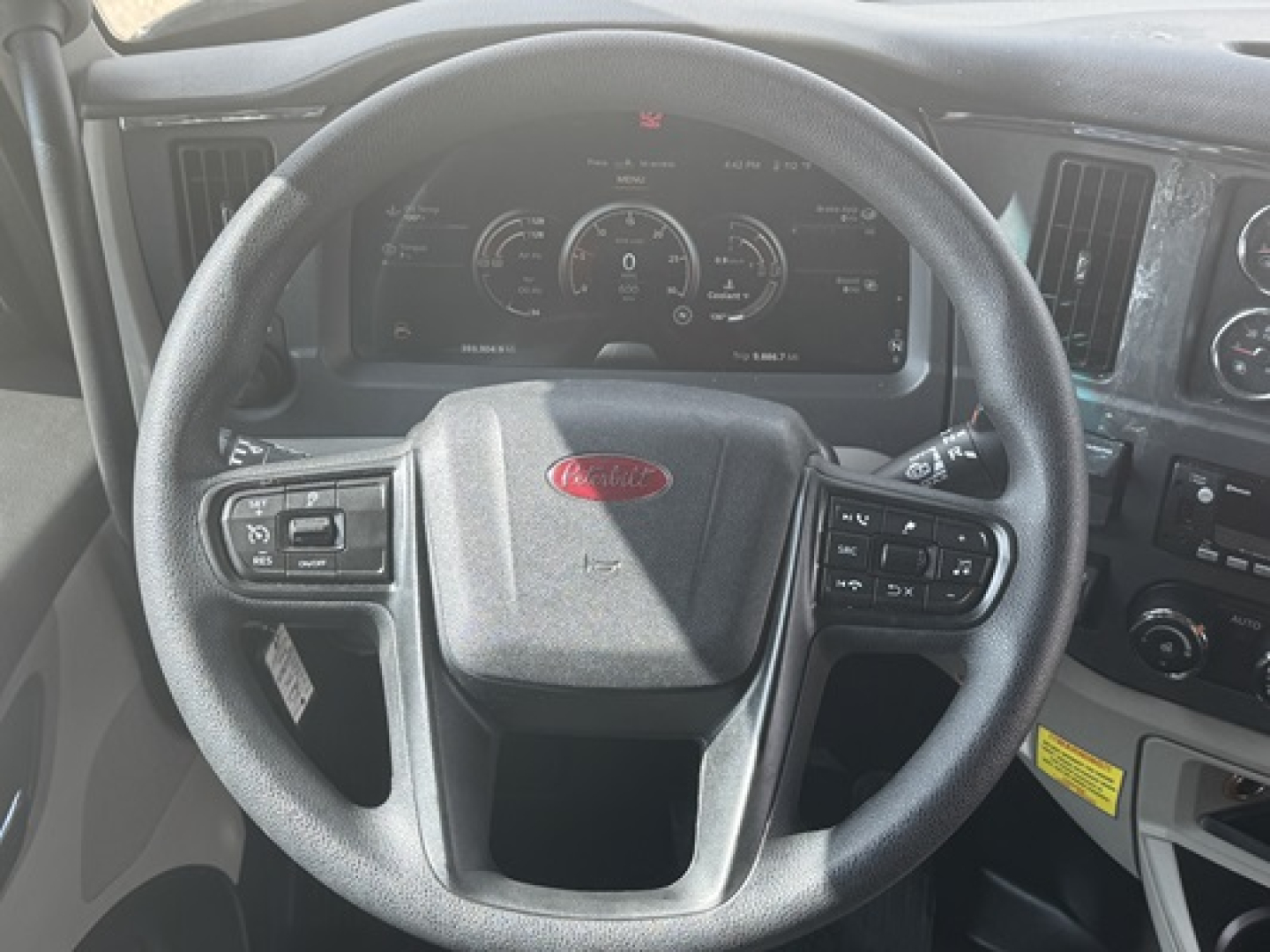 Peterbilt 579 cab interior showing steering wheel with Peterbilt logo and digital instrument cluster.