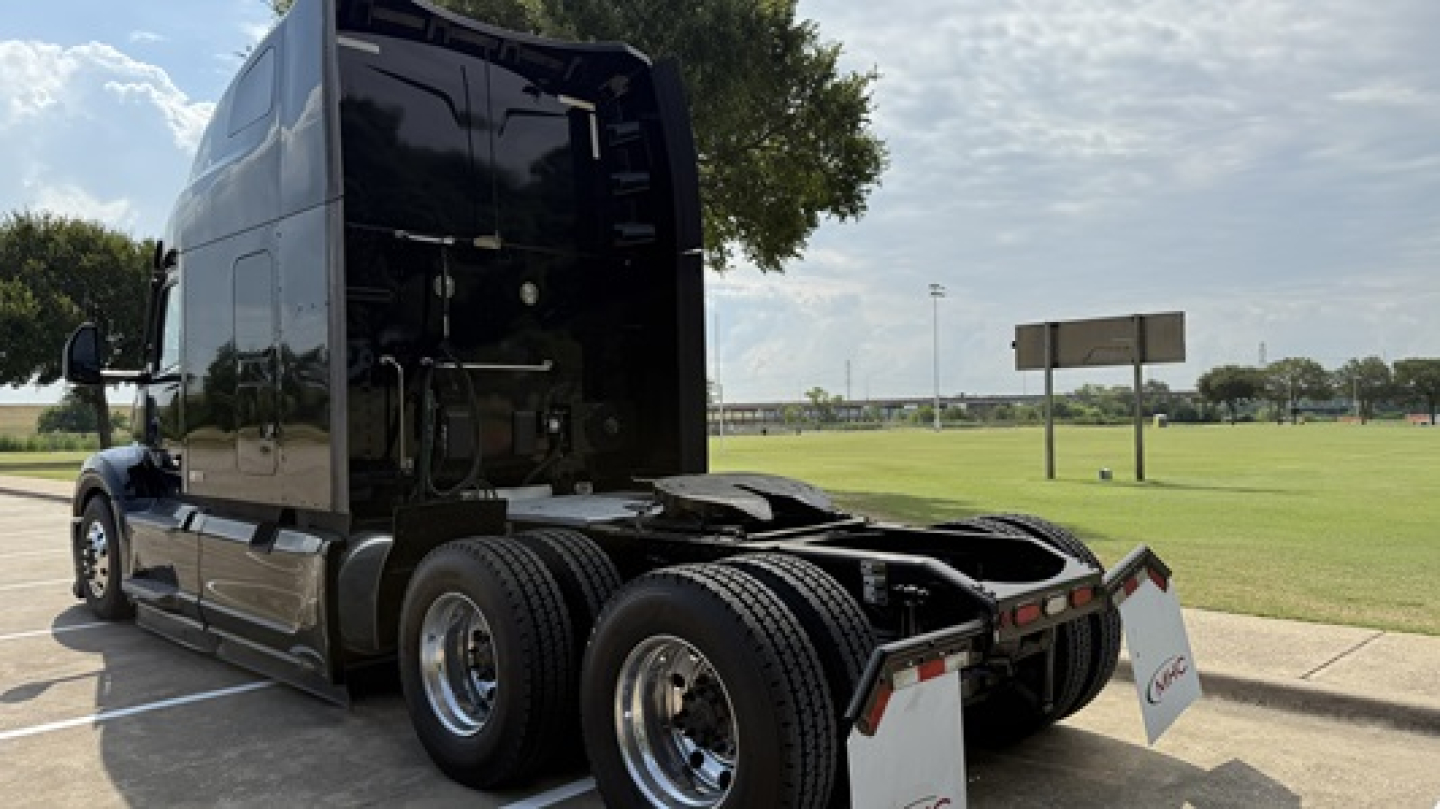 Peterbilt 579 tractor with tall sleeper cab, dual rear axles, chrome wheels, and visible fifth wheel, side view showing black exterior and rear mud flaps.