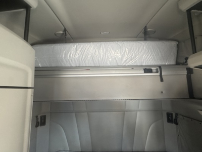 Trucks cab interior showing sleeper berth with mattress and storage shelves in a Peterbilt 579 cabin.
