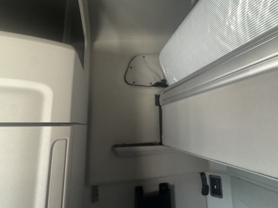 Peterbilt 579 cab interior view showing sleeper area and side panel, with a small storage shelf and window mount.