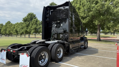 Peterbilt 579 tractor with sleeper, rear view showing dual rear axles and glossy black exterior.