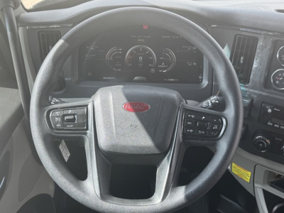 Peterbilt 579 cab interior showing steering wheel with Peterbilt logo and digital instrument cluster.