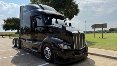 Peterbilt 579 tractor-trailer in black, front-left view, showing large chrome grille and sleeper cab.