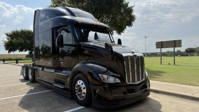 Peterbilt 579 truck side view in black with sleeper cab and chrome grille.