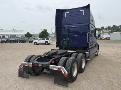 Volvo VNL 860 truck rear view showing dual rear axles and blue cab with fifth wheel, mud flaps, and rear tires.