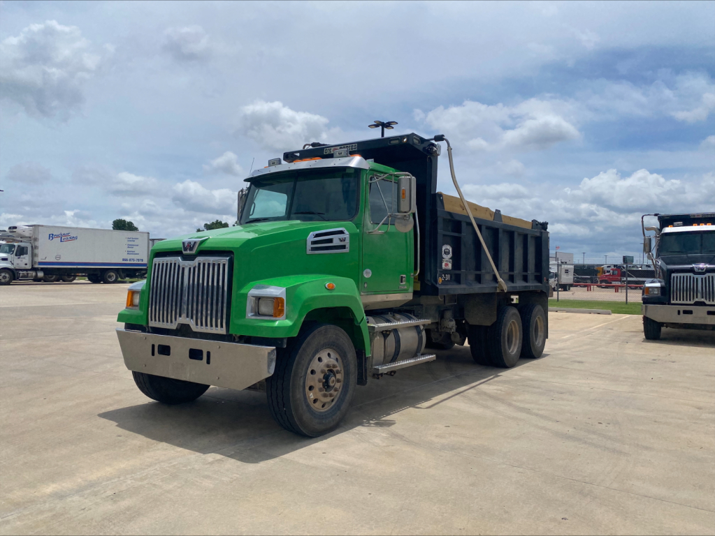 Green 2018 Western Star 4700SF dump truck in a parking lot, side view showing front grille, cab, and black dump bed.