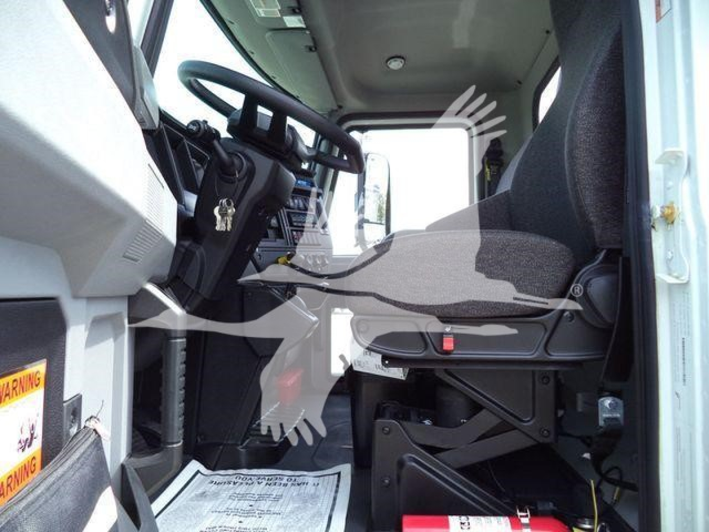 Truck cab interior of a 2027 Mack MD6 rollback truck showing driver seat and steering wheel with dashboard and pedals