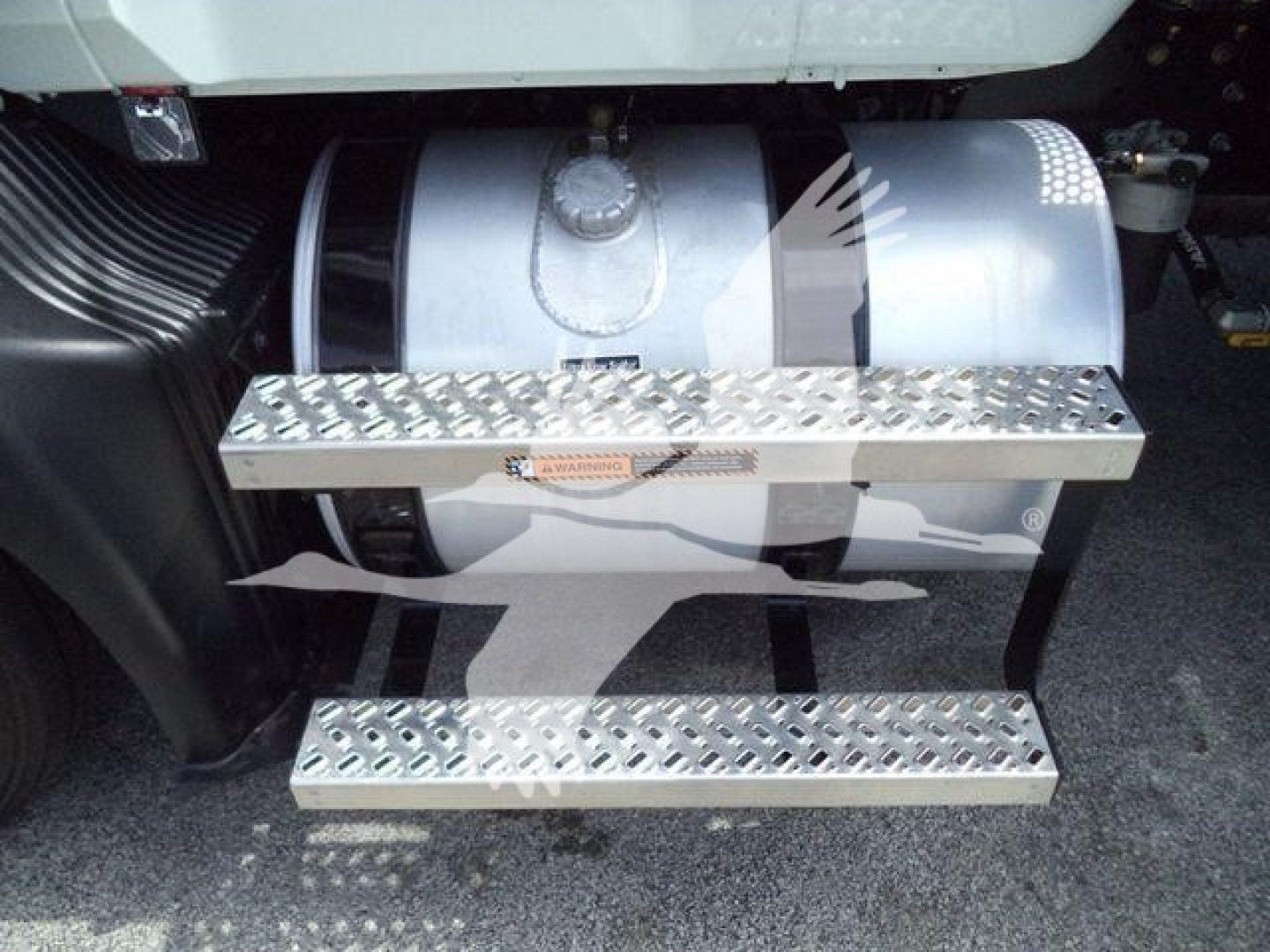 Truck side view showing fuel tank and diamond plate steps; metallic tanks and platforms visible under cab of a 2027 Mack MD6 rollback truck.