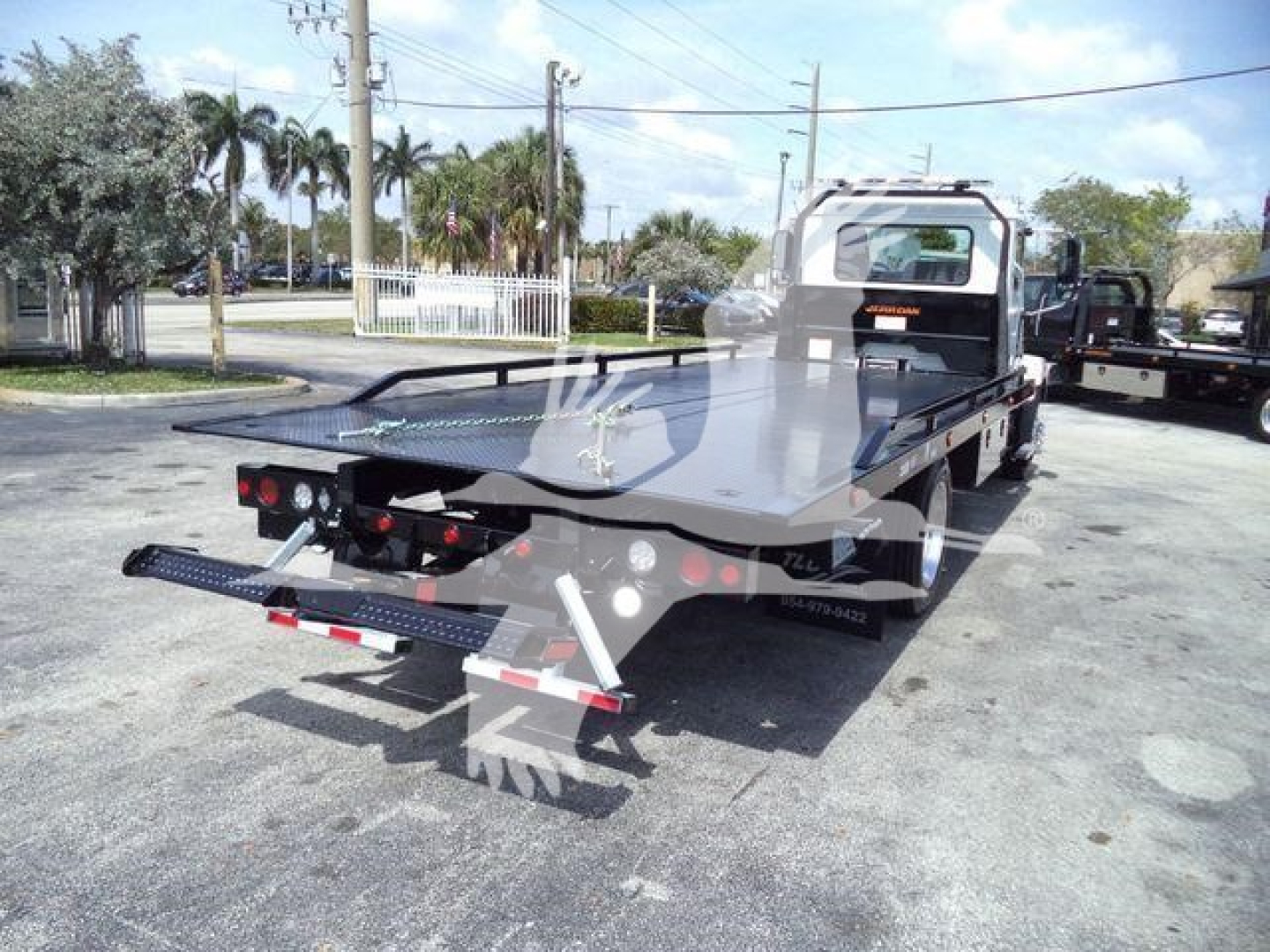Flatbed tow truck rear view showing loading deck and ramps on a 2027 Mack MD6 rollback truck.