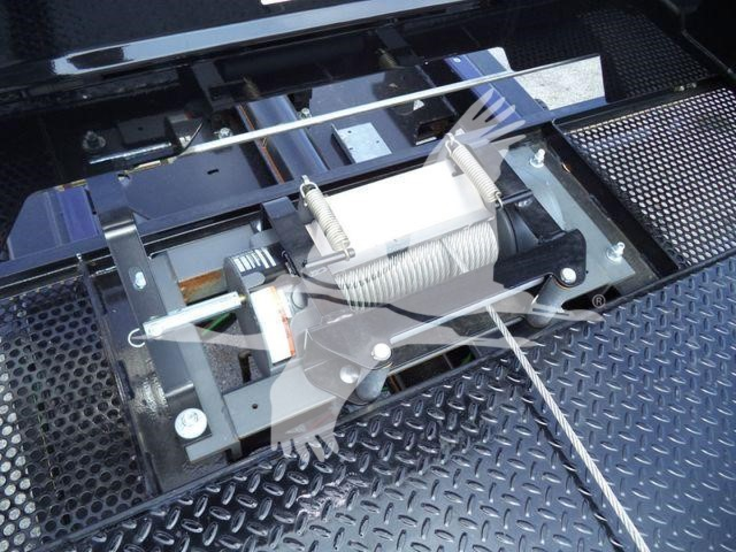 Trucks equipment bay showing winch assembly and mounting hardware in a diamond plate surface.