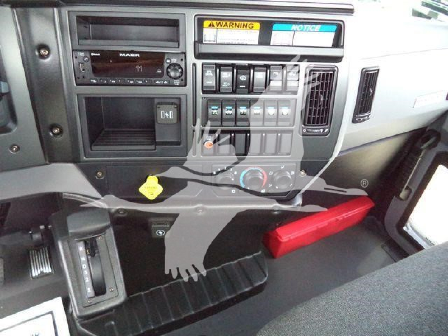 Mack MD6 dash and center console showing controls, radio, warning labels, and dashboard storage area.