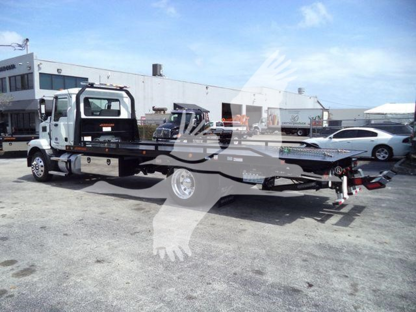 MD6 rollback truck on a lot showing a flatbed tow rig with white cab and black chassis, rear hitch and towing equipment visible.