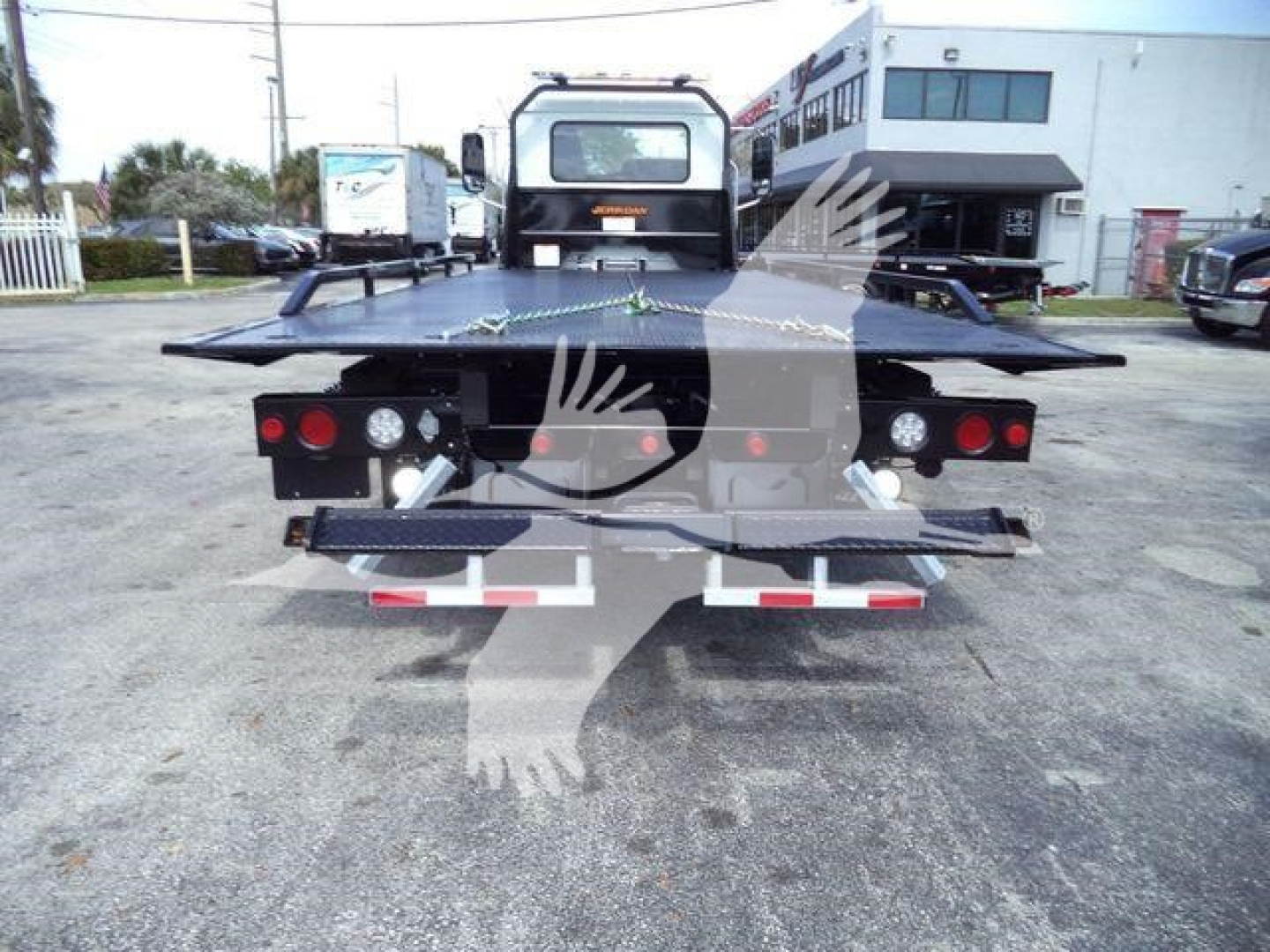 Rear view of a Mack MD6 rollback truck platform showing flatbed with taillights, license plate area, and towing equipment.