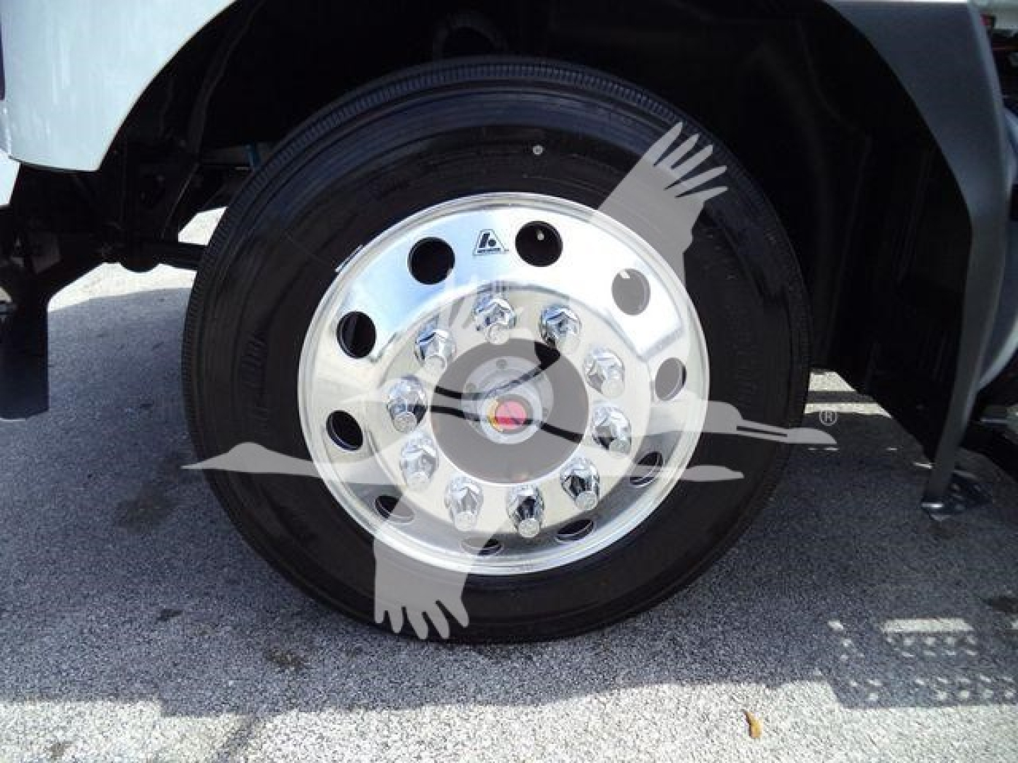Wheel close-up on Mack MD6 rollback truck showing chrome hub with multiple lug nuts and polished wheel cover.