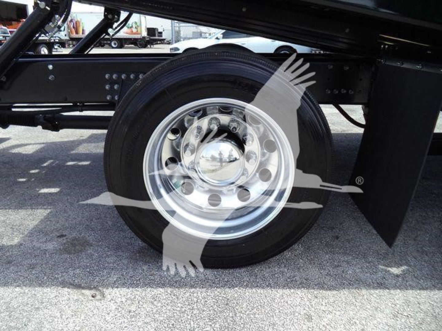 Wheel and suspension area of a new 2027 Mack MD6 rollback truck showing steel wheel and tire underframe with bolts and frame components.