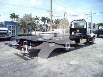 2027 Mack MD6 rollback truck viewed from side rear showing flatbed with towing equipment and cab; stock number J13303 visible in listing context.