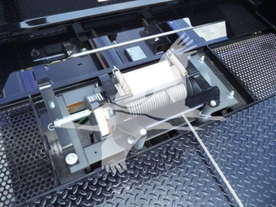 Trucks equipment bay showing winch assembly and mounting hardware in a diamond plate surface.