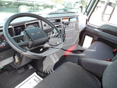 Interior of a Mack MD6 truck cab showing steering wheel with Mack logo, dashboard with controls and gear selector, driver's seat, and front passenger area.