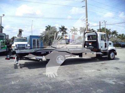Md6 tow truck on flatbed with rollback equipment and rear loading ramp visible.