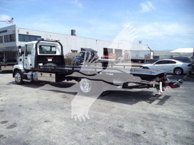 MD6 rollback truck on a lot showing a flatbed tow rig with white cab and black chassis, rear hitch and towing equipment visible.