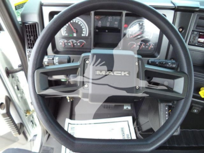 Steering wheel and dashboard of a Mack MD6 truck cab showing the Mack emblem; instrument cluster with gauges and a center display.
