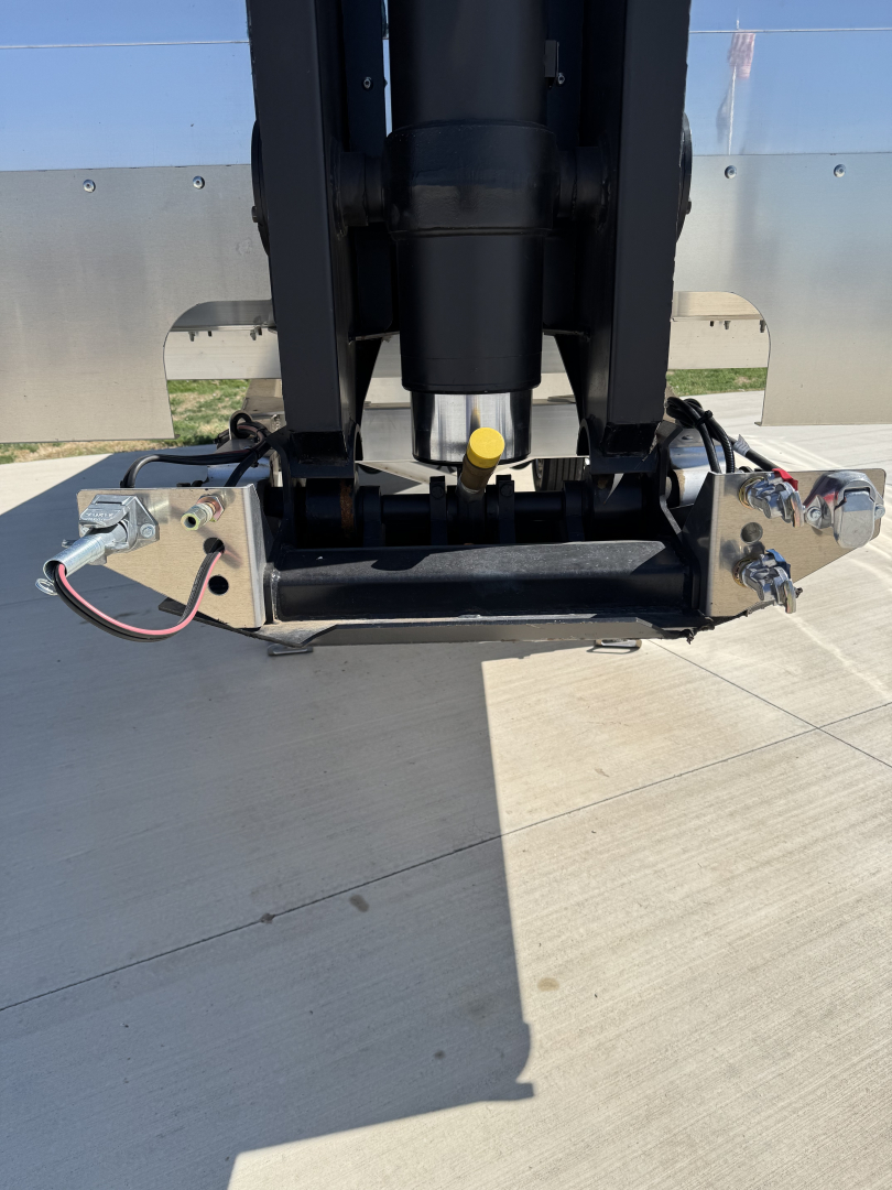Hicks FH2827 spread axle trailer hitch area showing hydraulic cylinder, mounting brackets, electrical connections, and control valve at the front edge.