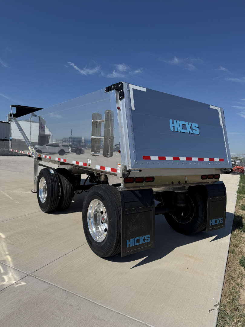 Hicks FL2827 spread axle dump trailer, aluminum hopper with blue Hicks logo on rear door, dual rear axles with mudflaps
