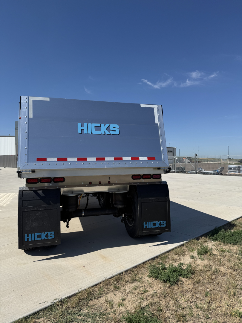 Trailer rear with Hicks branding showing dump trailer bed, taillights, and mud flaps reading HICKS.