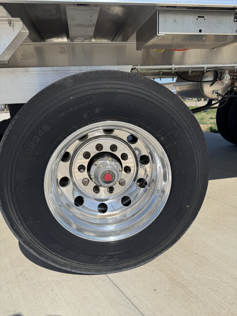 Trailer wheel showing chrome hub with lug nuts and black tire on Hicks FL2827 spread axle trailer.