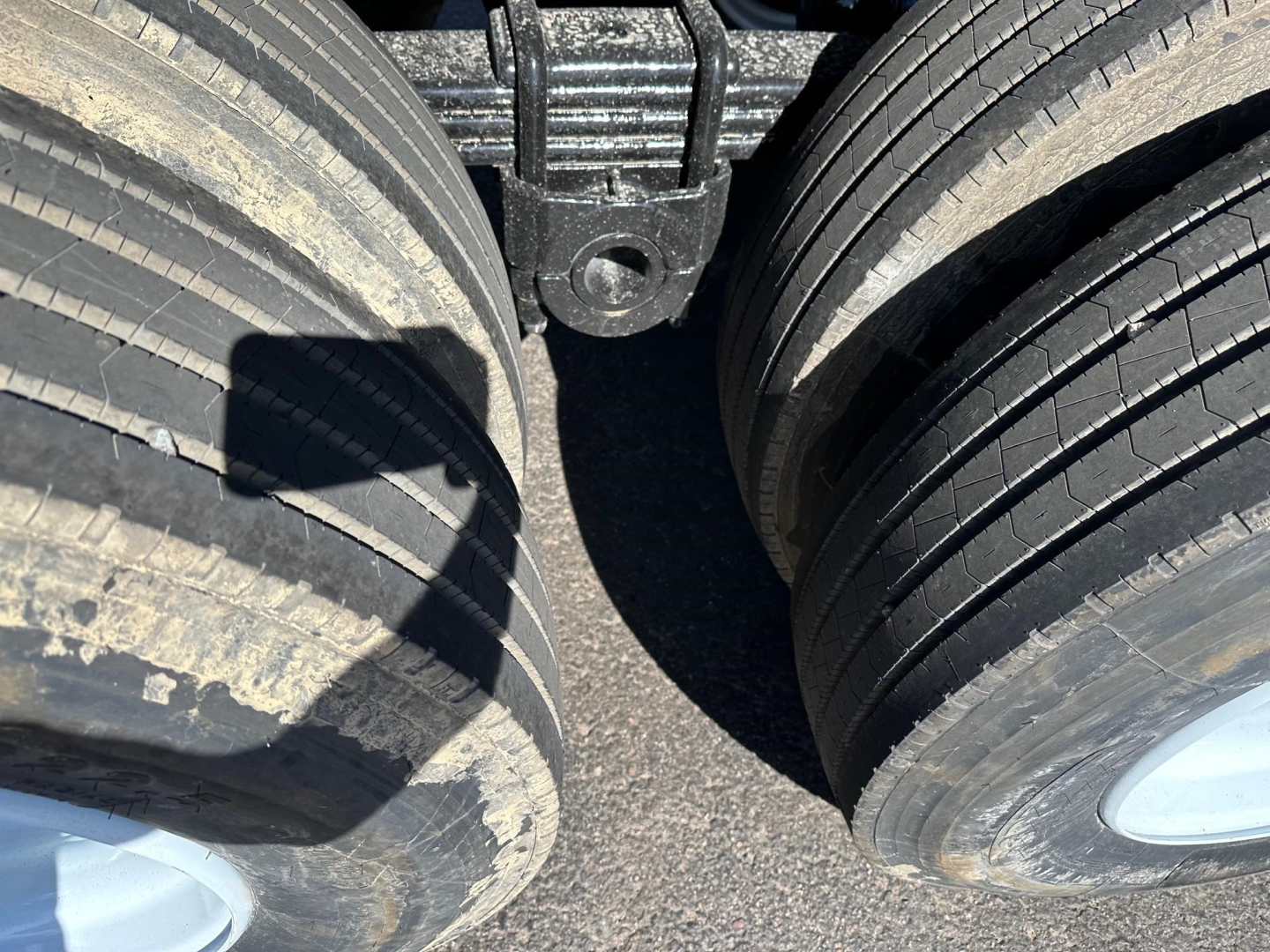 Dual rear trailer wheels and suspension components of a dump trailer showing tire treads and hub area.