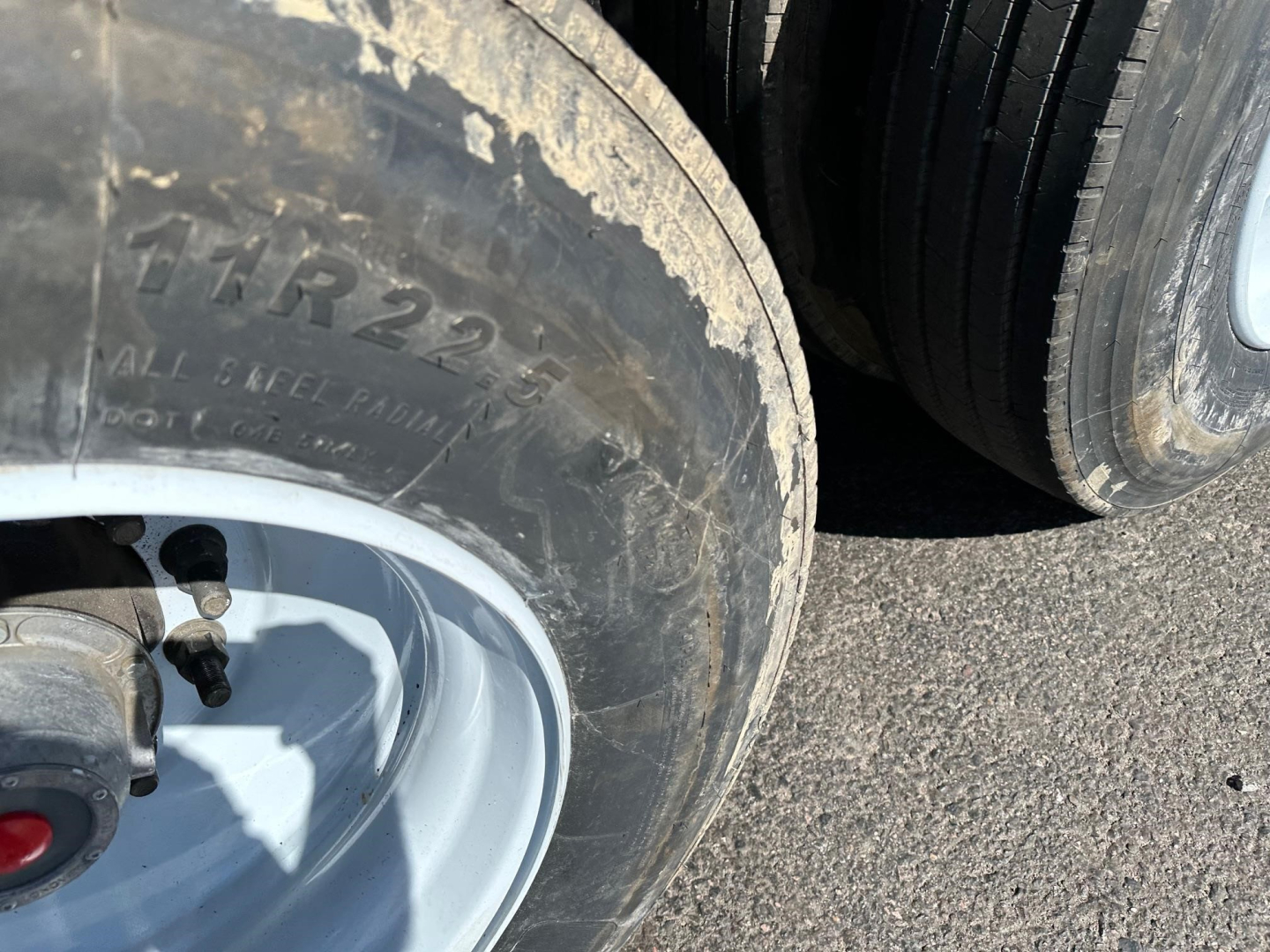 Tire and wheel of a trailer showing part of the tire and rim with dirt and grime.