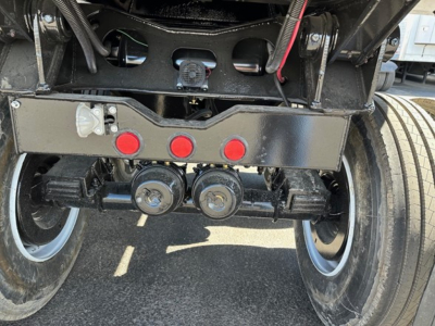 Rear view of a 2025 Ranco Quarter Frame Steel End Dump trailer showing dual axle hubs, suspension components, and wiring harnesses beneath the frame.
