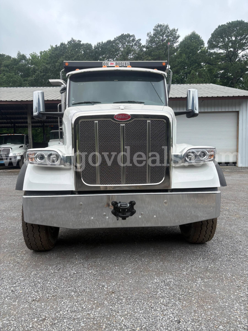 Peterbilt 377 front view showing chrome grille, large bumper, and dual headlights; white cab, side mirrors, and cargo truck.