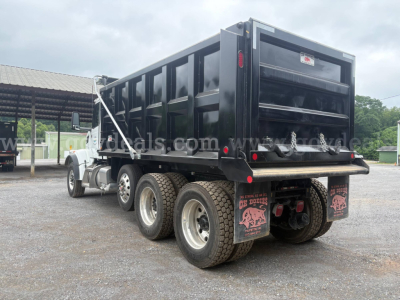 Peterbilt 377 dump truck rear-left view showing dump bed, dual rear axles, mud flaps, and rear bumper with taillights.