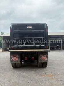 Peterbilt 377 dump truck rear view showing dump bed and dual rear wheels with mud flaps and chains.