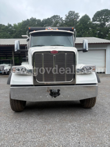 Peterbilt 377 front view showing chrome grille, large bumper, and dual headlights; white cab, side mirrors, and cargo truck.