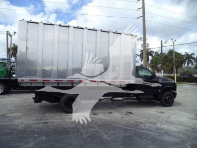 Truck body showing a silver cargo dump bed on a black Chevrolet Silverado 6500HD chassis in a lot.