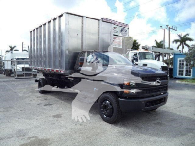 Chevrolet Silverado 6500HD truck with a silver dumping cargo box in a dealership lot.
