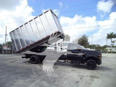 Truck bed tilted with hydraulic tilting dump on Chevrolet Silverado 6500HD, black cab, metal cargo container raised at an angle.
