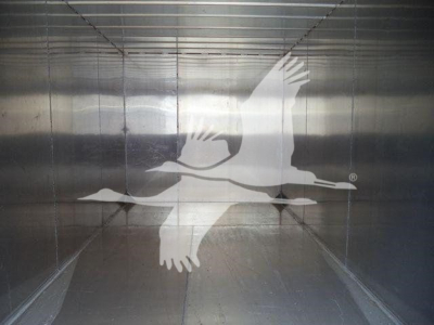 Truck trailer interior image with a large white bird silhouette (possibly a crane) covering the scene.