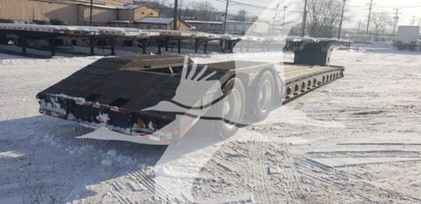 Lowboy trailer showing beavertail extendable flatbed with multiple axles and rear lights.