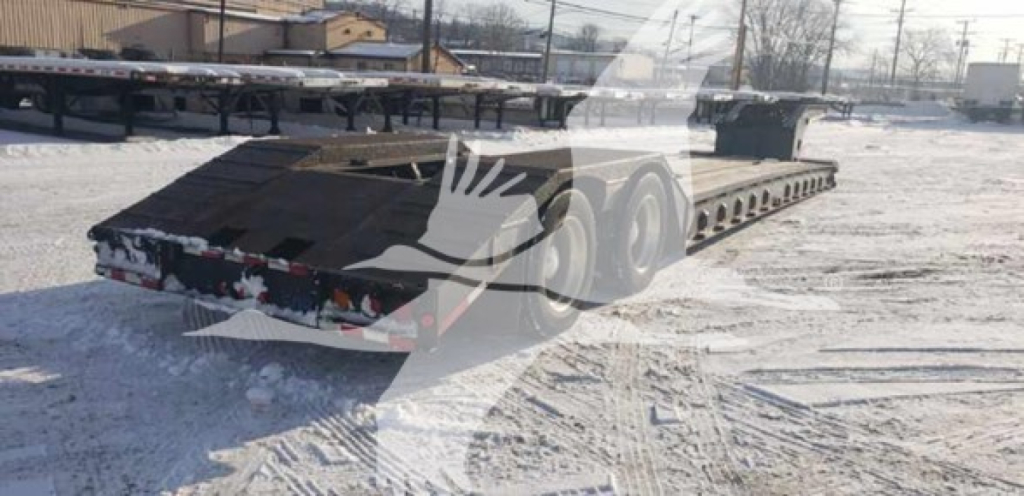 Lowboy trailer showing beavertail extendable flatbed with multiple axles and rear lights.